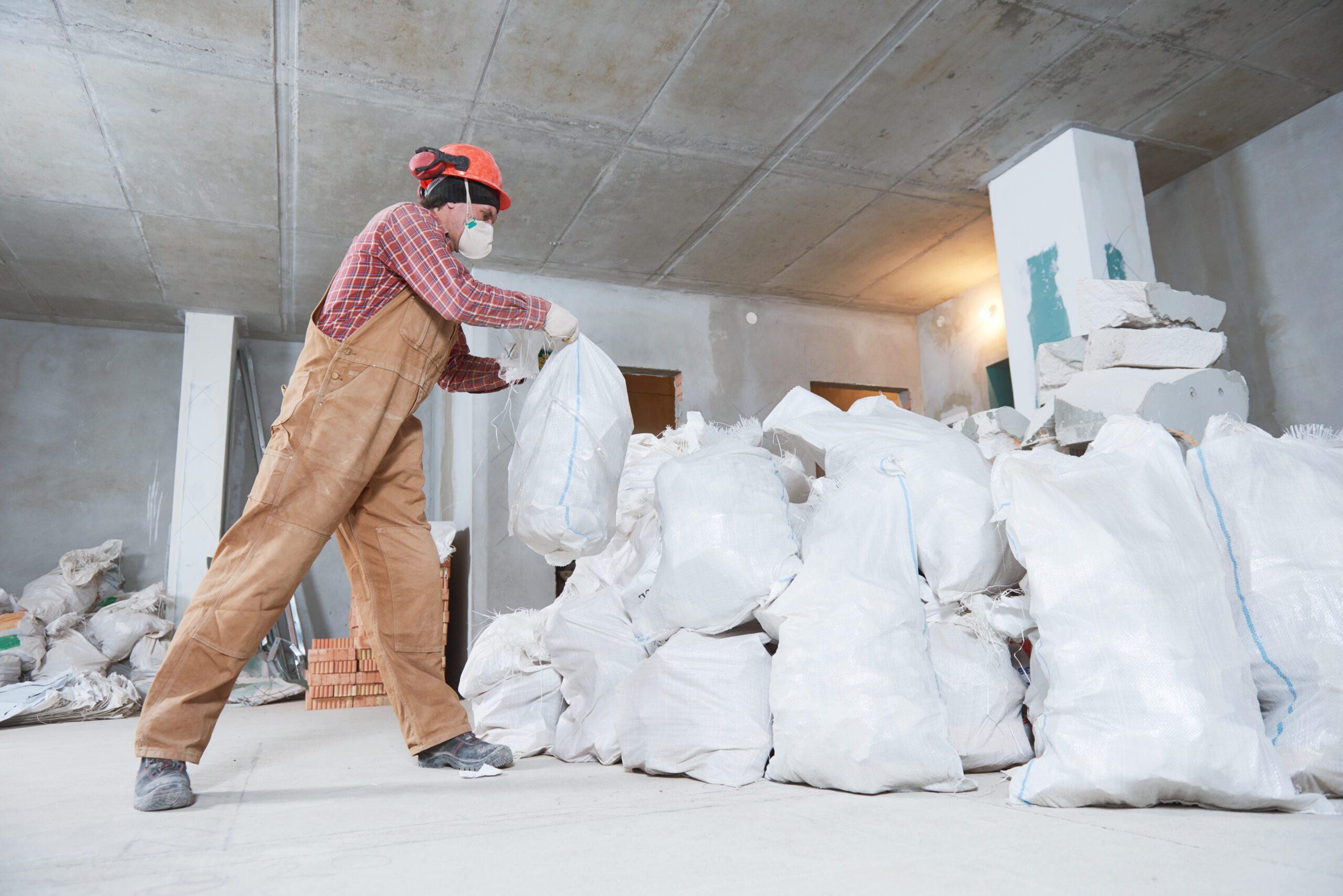 Worker Collecting Construction Waste in Bag
